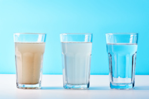 Three glasses on a white-blue background show the process of filtering tannins from water to obtain clean water using water filters. Concept of tannins in water.